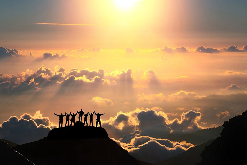 people on a mountain with the sun and sky